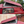 Charger l'image dans la galerie, A red pop-up camper roof tent shown in two stacked photos, demonstrating the upper compartment with the lid open and the lower compartment with the tent pitched. The background shows trees and an outdoor brick wall.
